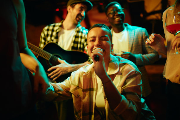 一名年轻的黑人女子与朋友在酒吧的晚间派对上唱歌。图片下载