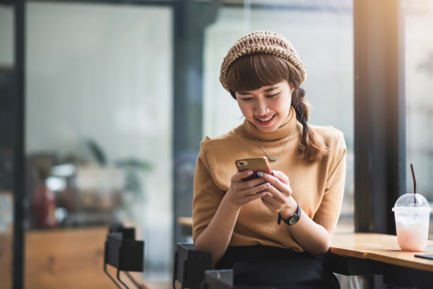 年轻的亚洲女性喜欢在café上玩手机。图片下载