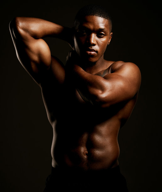 摄影棚拍摄了一个健康的年轻男子在黑色背景下摆姿势图片下载