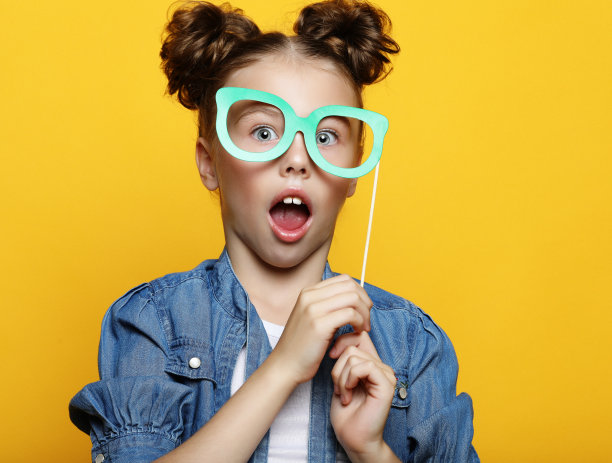 小女孩在黄色背景上拿着纸饰品图片下载