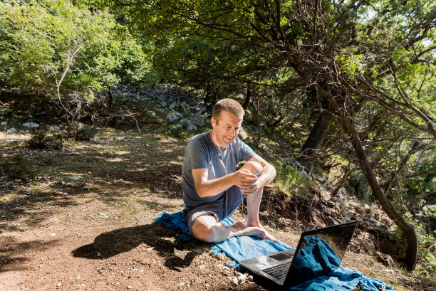 自由企业家用他的笔记本电脑在大自然的远程位置作为数字游牧民工作图片下载