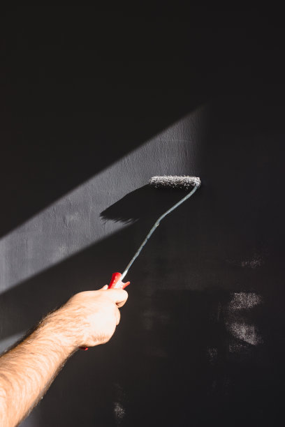 男人的手在刷灰色的墙漆图片下载