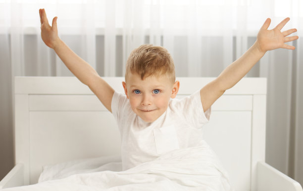 蓝眼睛的男孩早上在床上醒来时微笑着图片下载