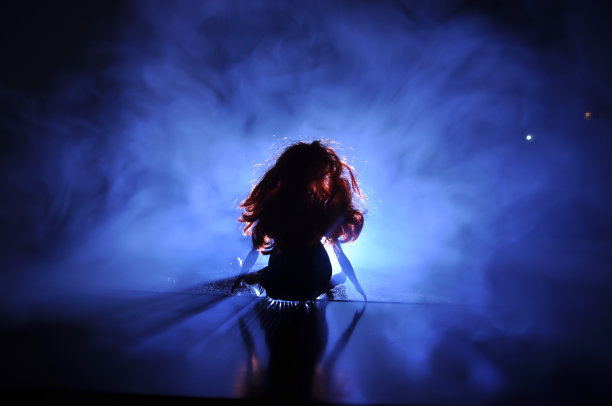 在浅色背景上的女性脸的剪影。一个长发的孤独娃娃的剪影，透过窗户的背光看到的城市风景图片下载