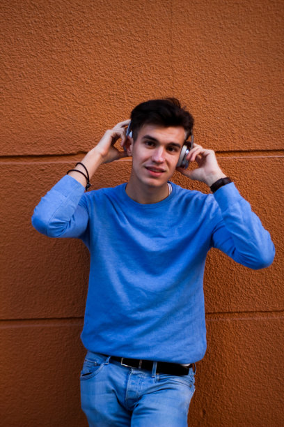 一个戴着耳机听音乐的年轻人的竖像图片下载