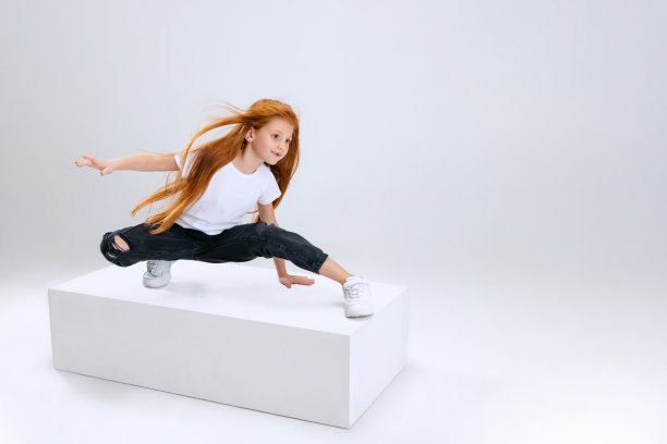小白人女孩的肖像，孩子在白色的工作室背景下孤立。在盒子上保持平衡图片下载