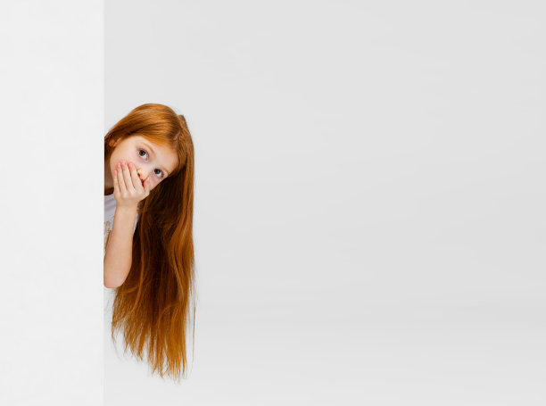 俏皮小女孩的裁剪肖像，小学生望出角落孤立的白色背景图片下载