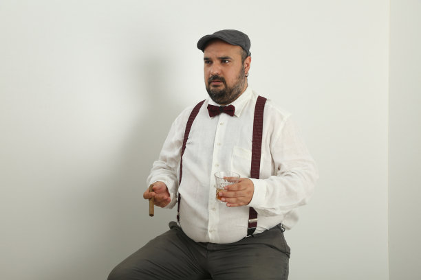 穿着亚麻衬衫和衣架，抽着雪茄和威士忌，用手势说着什么的年轻男人图片下载