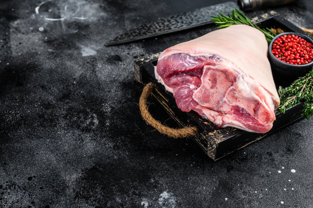 新鲜的生猪肉艾斯拜因关节火腿在木制托盘和肉刀。黑色木制背景。前视图。本空间图片下载