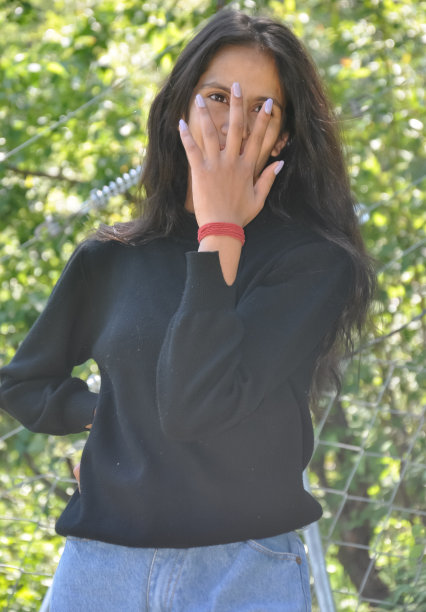 一个穿着休闲装的年轻女孩的肖像，在户外用手遮住她的脸图片下载