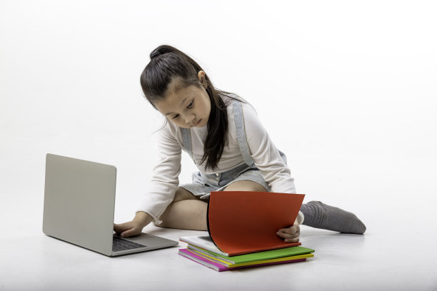 女孩坐着看书，在学校使用笔记本电脑，乐趣和快乐，教育理念，学习和知识。图片下载