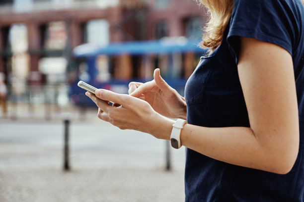 一名女子在城市街道上使用智能手机图片下载