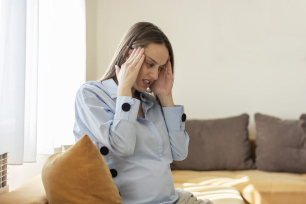 孕妇坐在家里的沙发上头痛图片下载