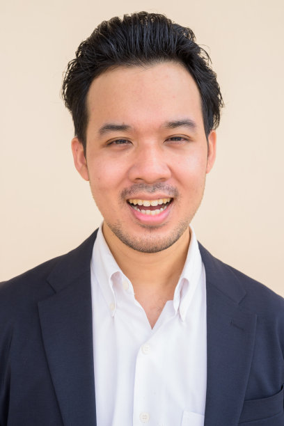 亚洲商人的肖像，身穿西装，背景朴素，面带微笑图片下载