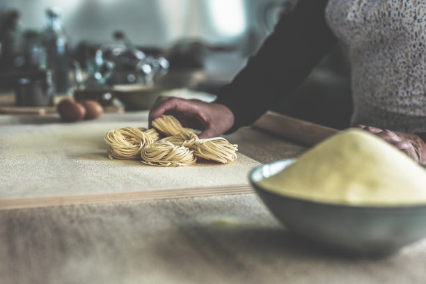 自制意面的特写-妇女正在工厂里制作新鲜的意大利传统意面图片下载