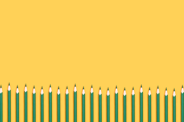 黄色背景上的一排绿色铅笔。图片下载