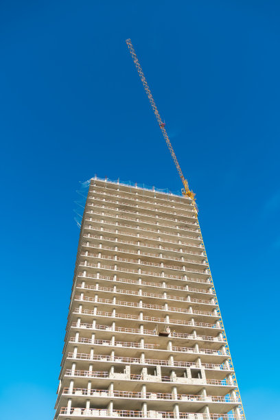 多层在建建筑，黄色施工起重机，蓝天背景，复制空间。垂直图图片下载