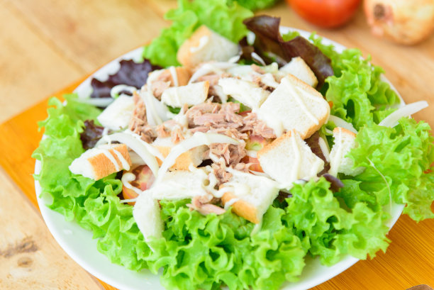 靠近金枪鱼沙拉在白色盘子上的木盘图片下载