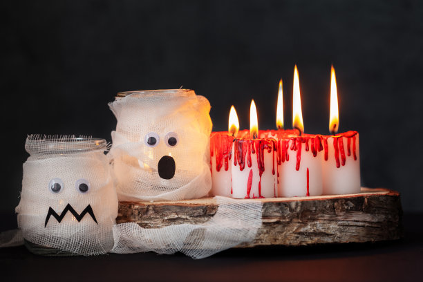 在黑暗的背景下，燃烧的蜡烛和罐子里的木乃伊。红蜡覆盖的白色蜡烛像血滴。万圣节的节日的概念。图片下载