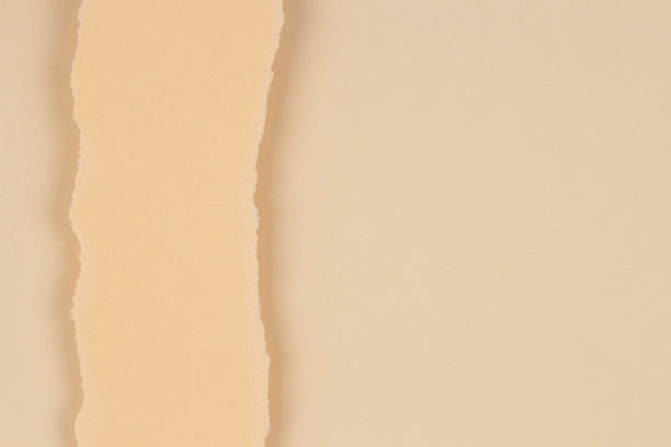 在空白的米色背景上撕裂的垂直纸片。抽象单色土色背景图片下载