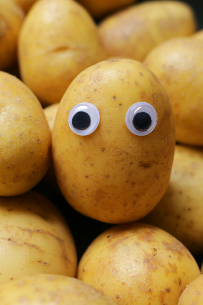 全帧图像婴儿新土豆在一堆，大眼睛添加到一个土豆给蔬菜一个担心的表情，幽默的概念图片下载