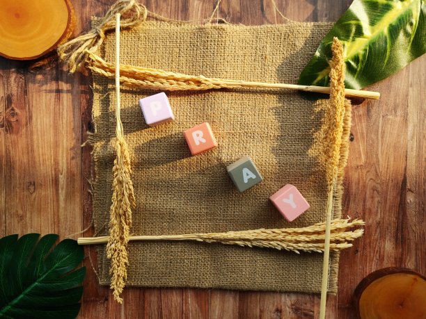 组成“祈祷”这个词的木块，背景是粗麻袋、树叶和树干图片下载