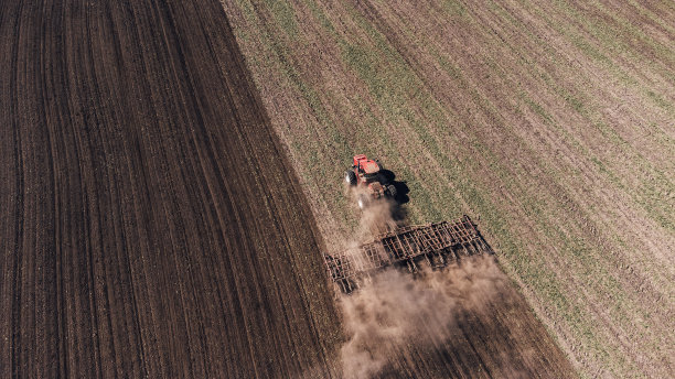 鸟瞰图农业拖拉机犁地和喷洒。农业。从以上观点。无人机拍摄的照片。图片下载