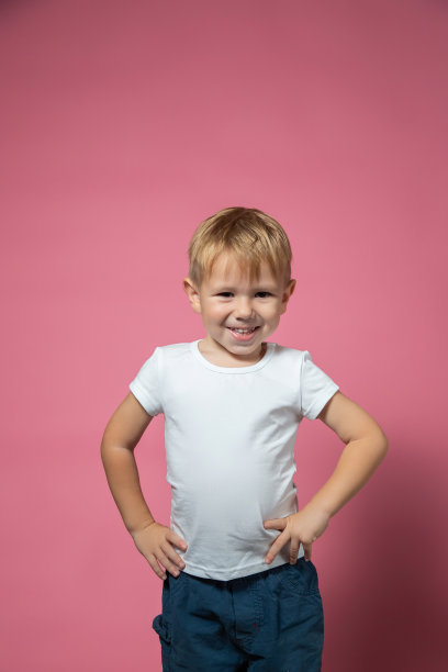 Ð一个高加索男孩在粉红色的背景上看着摄像机做鬼脸图片下载