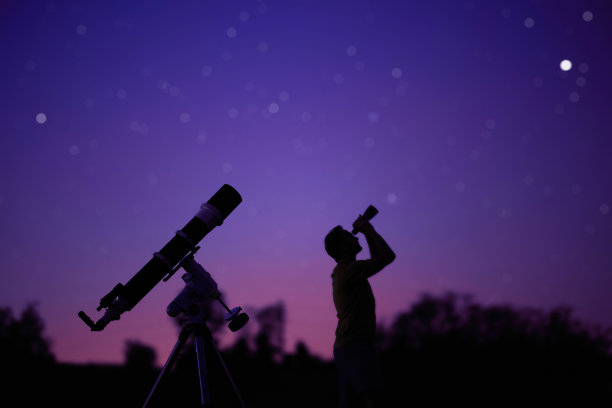 一个人的剪影，望远镜和星空下的乡村。图片下载