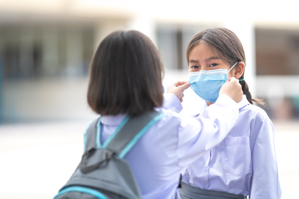 在新冠肺炎疫情形势好转后，孩子们穿着校服，戴着防护口罩互相上学。回到学校概念库存照片图片下载