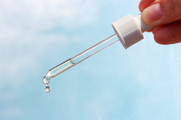 女性手持滴管与血清的背景上的天空。图片下载