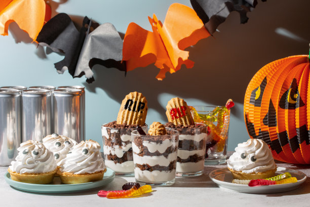 万圣节派对的糖果。万圣节糖果自助餐。墓地蛋糕杯，幽灵蛋白馅饼和可怕的口香糖在万圣节的装饰品。图片下载