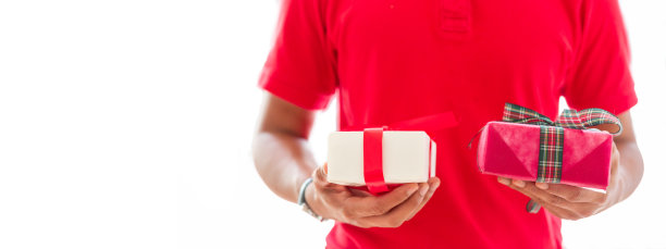 穿着红色制服的快递员手里拿着白色背景的包裹，上面有复印的地方。快递包裹运输在线到家图片下载