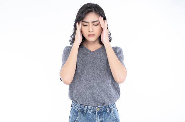 美丽的年轻亚洲女人的肖像在灰色t恤和牛仔裤遭受头痛绝望和压力，因为疼痛和偏头痛孤立在白色的背景。图片下载