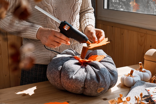 舒适的南瓜。一位妇女正在制作彩色织物南瓜。木桌上的手工南瓜装饰。共鸣。感恩节装饰。图片下载