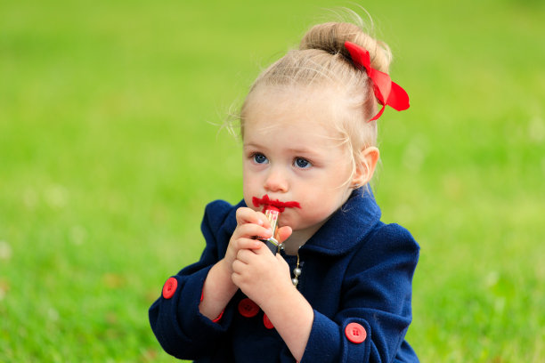 那孩子坐着用红色的口红涂嘴唇图片下载