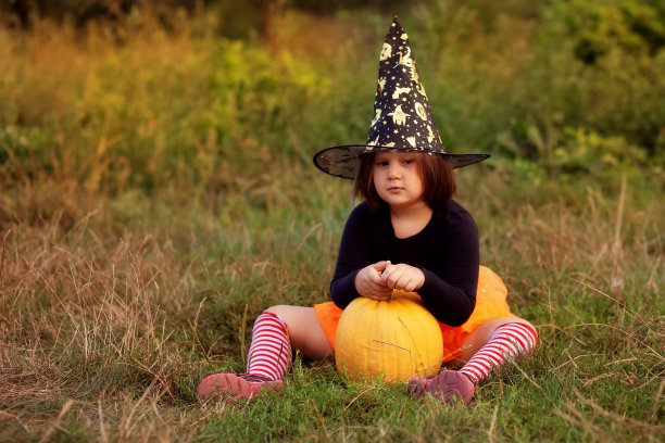 有趣的小女孩在万圣节的女巫服装与南瓜和橙色气球户外图片下载