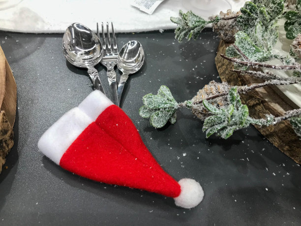 圣诞餐桌设置叉子，勺子和刀装饰锥，弓，树枝上的雪背景，新年和圣诞节的节日概念图片下载