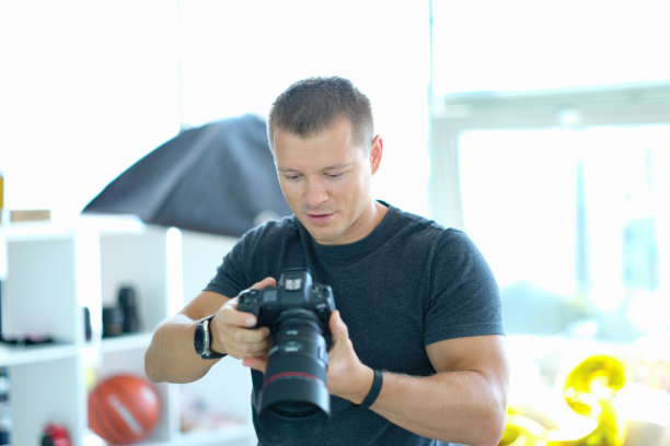 摄影棚里一名手持黑色专业相机的男摄影师图片下载