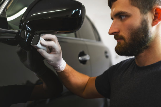 侧面照片，一名男子汽车抛光工人使用保护手套抛光和抛光车辆与陶瓷，使汽车闪闪发光。图片下载