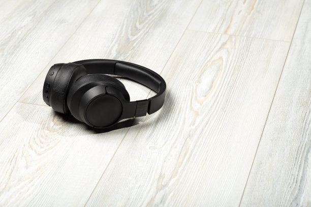 无线耳机在白色木地板的背景。隔音，音乐和声音在房间的概念。图片下载
