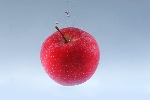 苹果在浅色背景下落入水中图片下载
