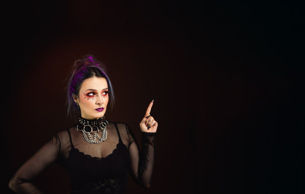 紫色头发哥特女人手指，万圣节化妆和疯狂的表情黑暗的背景图片下载