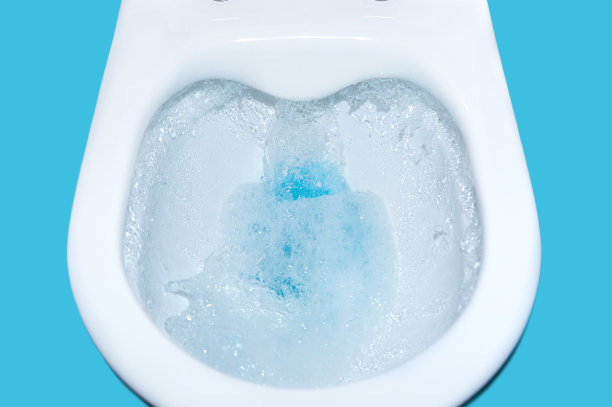 水从排水沟里往下流。抽水马桶用蓝色清洗液隔离。清洁厕所特写。图片下载