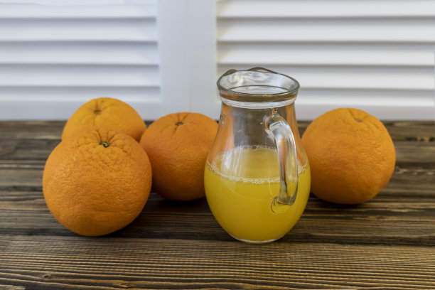 照片，在木制棕色背景上放着橙子和橙汁的罐子图片下载