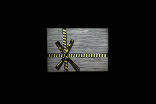 离焦一个礼物与金弓在黑暗的黑色背景。水平复制空间。灰色男性礼品盒，男人，男人，父亲。奢侈品包礼物。极简主义。的焦点图片下载