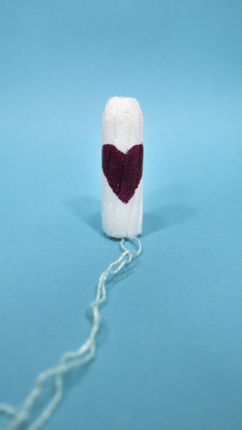 蓝色背景上有颗红心的卫生棉条。妇女的月经周期与生殖健康。图片下载