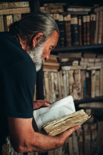 一个在图书馆里拿着一本旧书的老人图片下载
