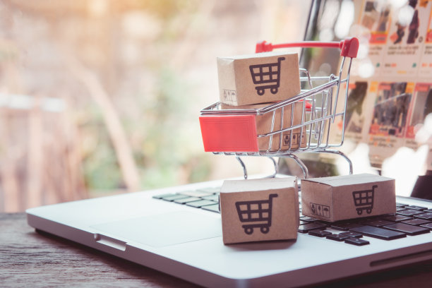 在线购物。带有购物车标志的纸板箱，手推车上有笔记本电脑键盘。网上购物服务。提供送货上门图片下载