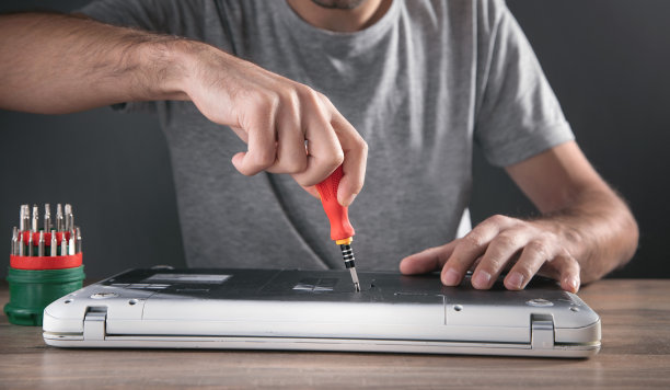 一名男子用螺丝刀拆卸笔记本电脑。图片下载